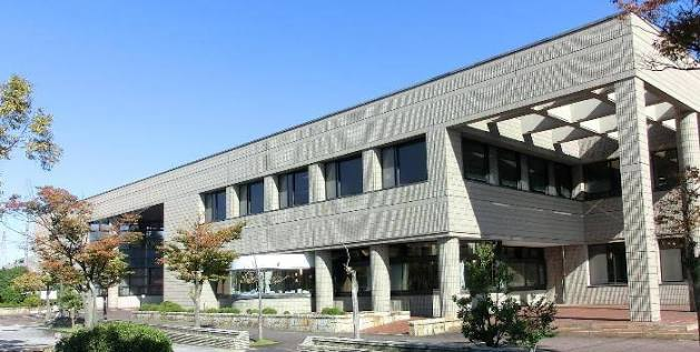 街路樹と植え込みに囲まれた二階建ての建物
