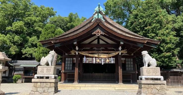 木々を背にした狛犬としめ縄のある神社の拝殿