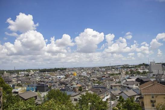 青空と雲の下に広がる住宅地の眺め