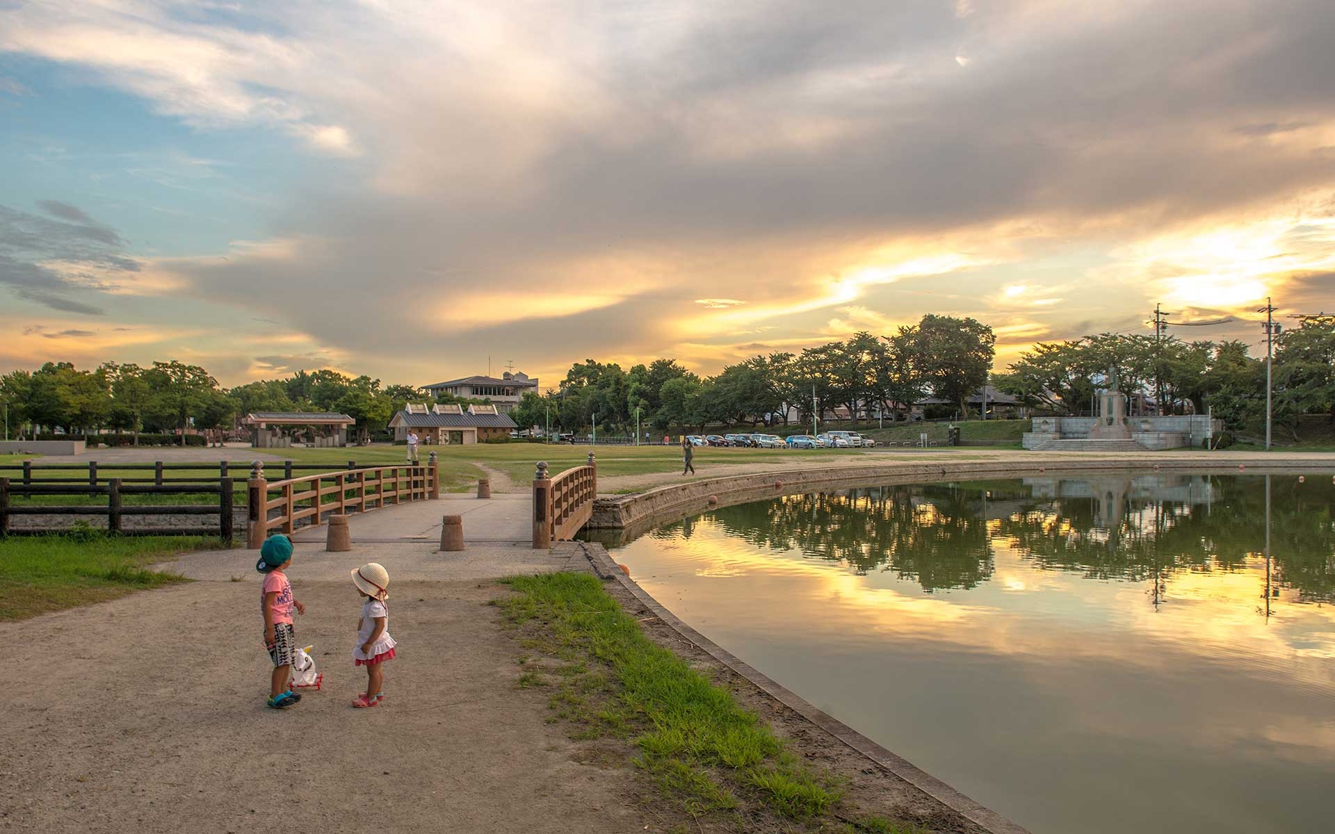 夕暮れの天王川公園の水辺と散策する人々